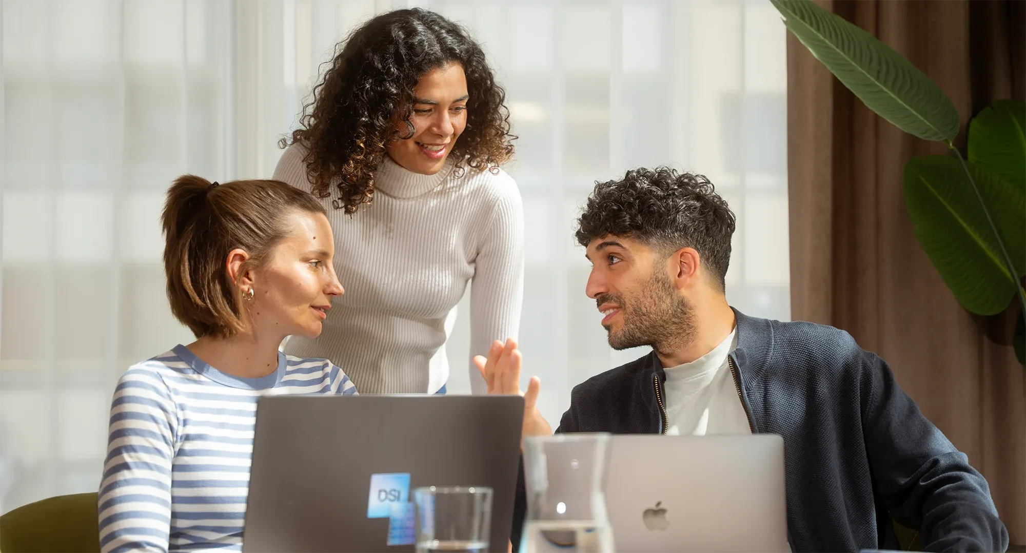 Drei Teammitglieder in einer Besprechung an ihren Laptops
