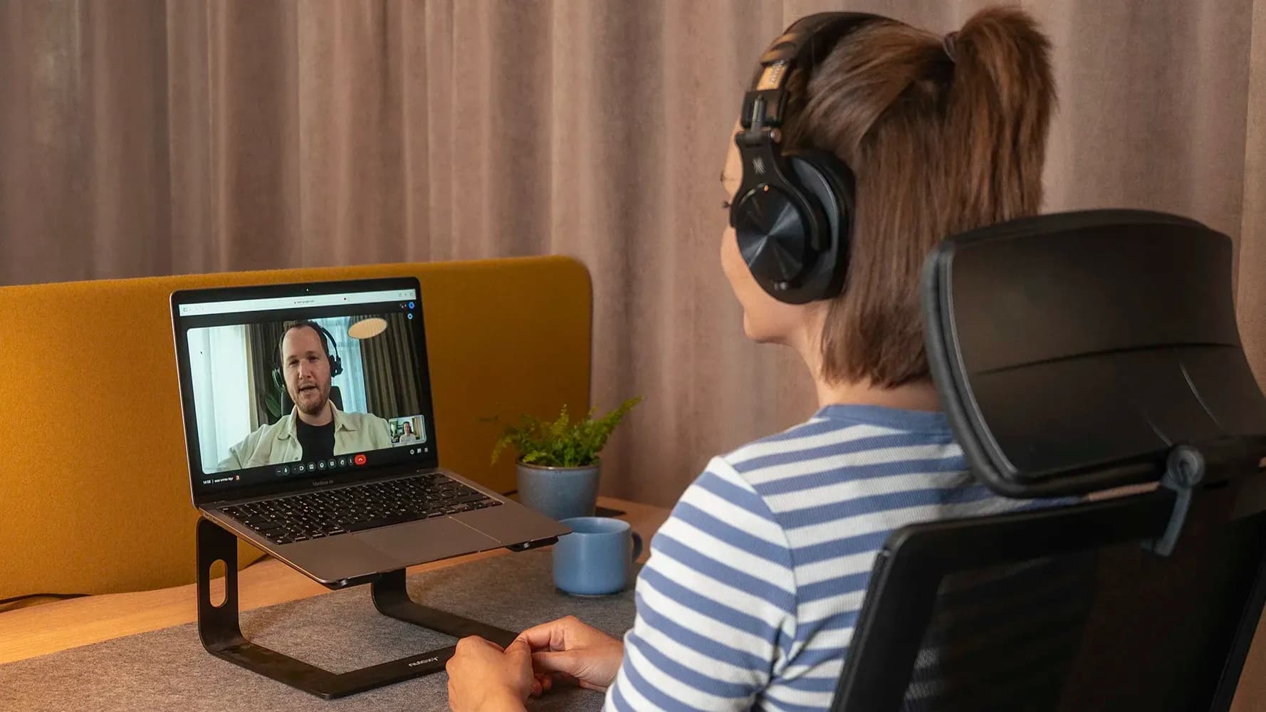 Mitarbeiterin mit Headset in einer Videokonferenz am Laptop